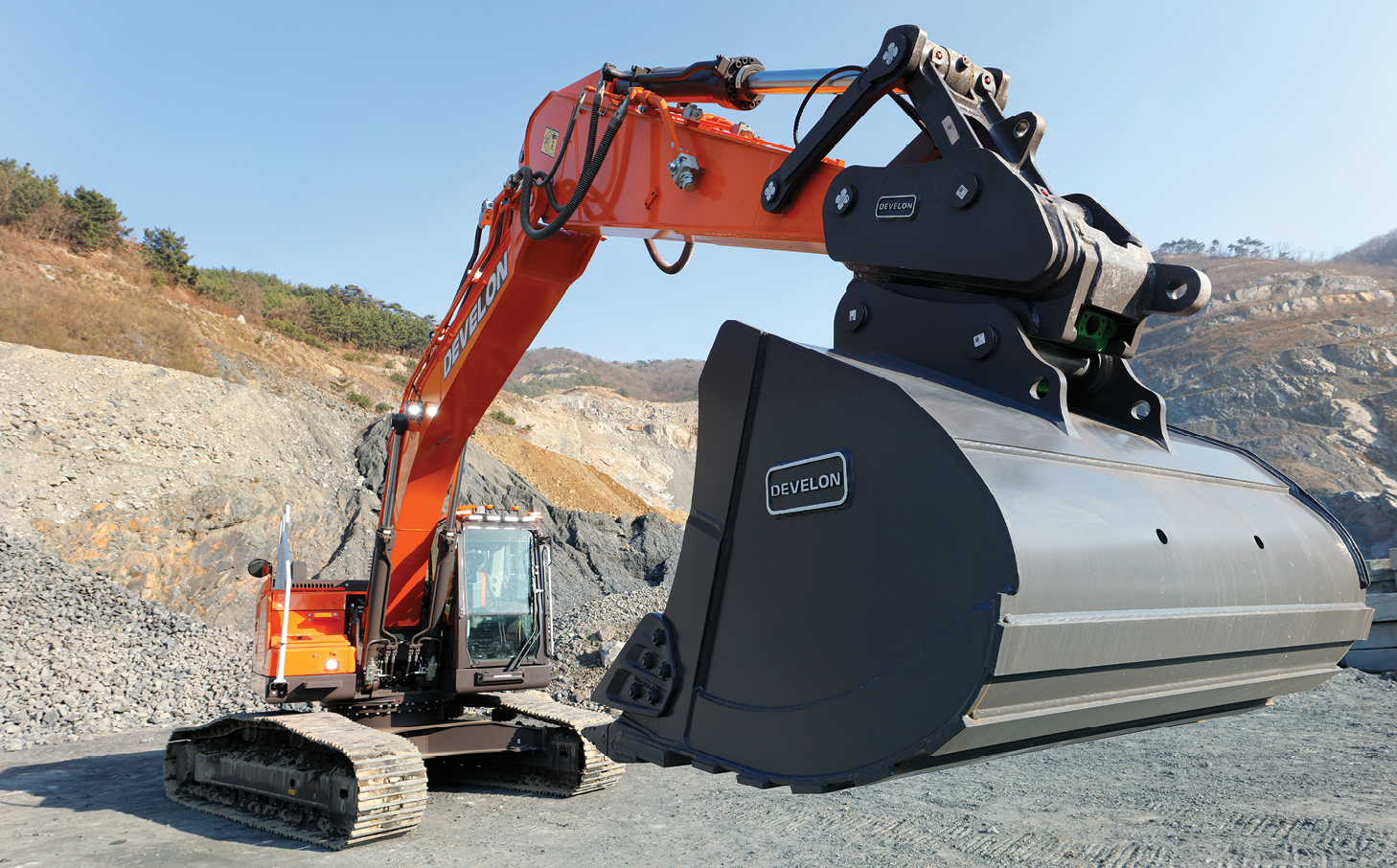 View of a DEVELON crawler excavator bucket in a raised position.
