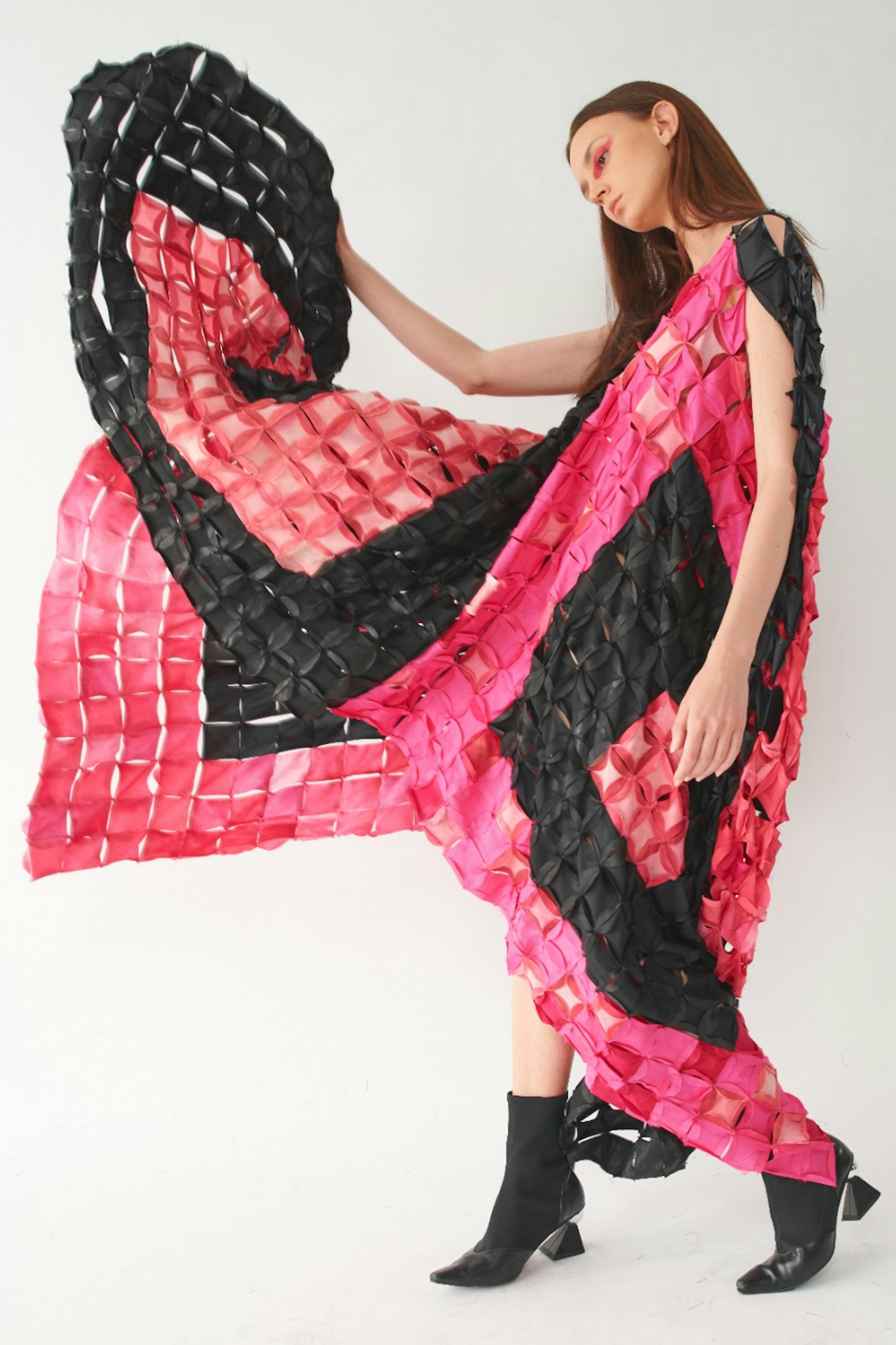 A model wearing an elaborate black and pink garment made from fabric dyed using bacteria.