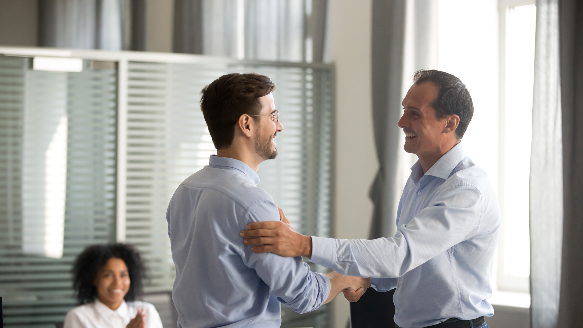 Smiling middle-aged ceo handshaking successful male worker showing respect