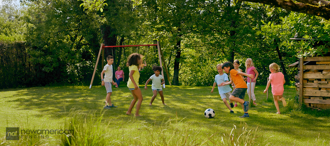 A diverse group of happy children play soccer in a nice backyard