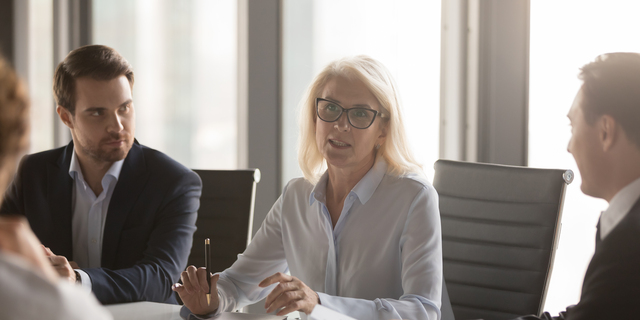 Serious middle aged businesswoman talks at group board executive meeting