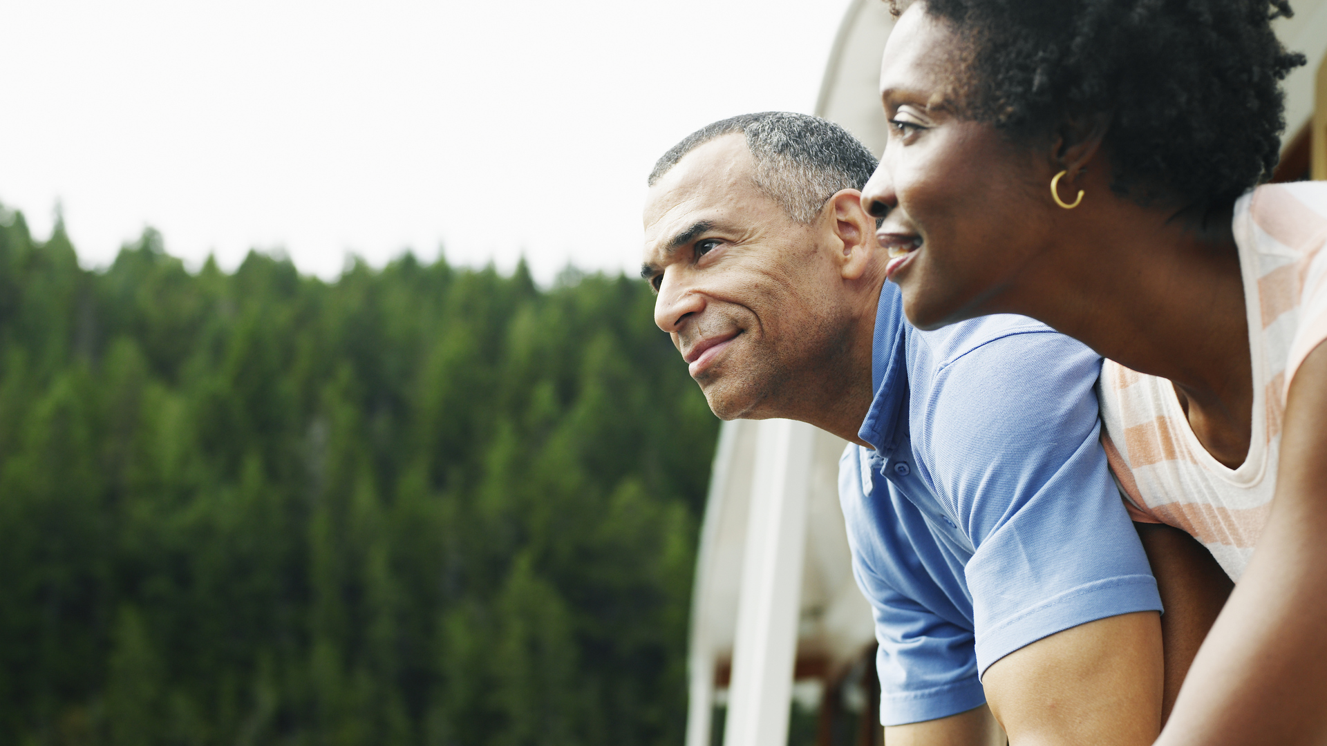 Mature couple on deck of yacht looking at view, smiling