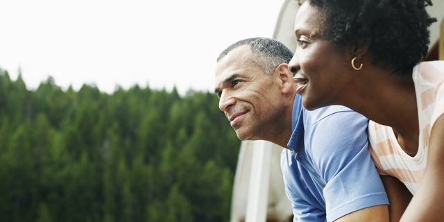 Mature couple on deck of yacht looking at view, smiling