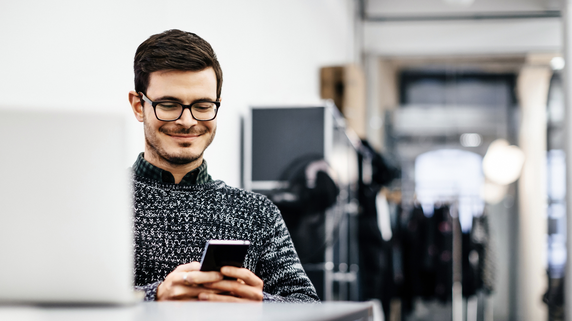 Young casual businessman looking at his smartphone