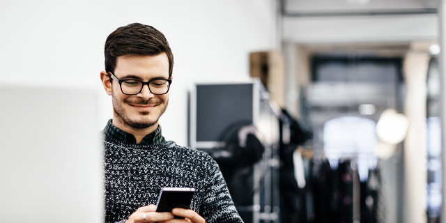 Young casual businessman looking at his smartphone