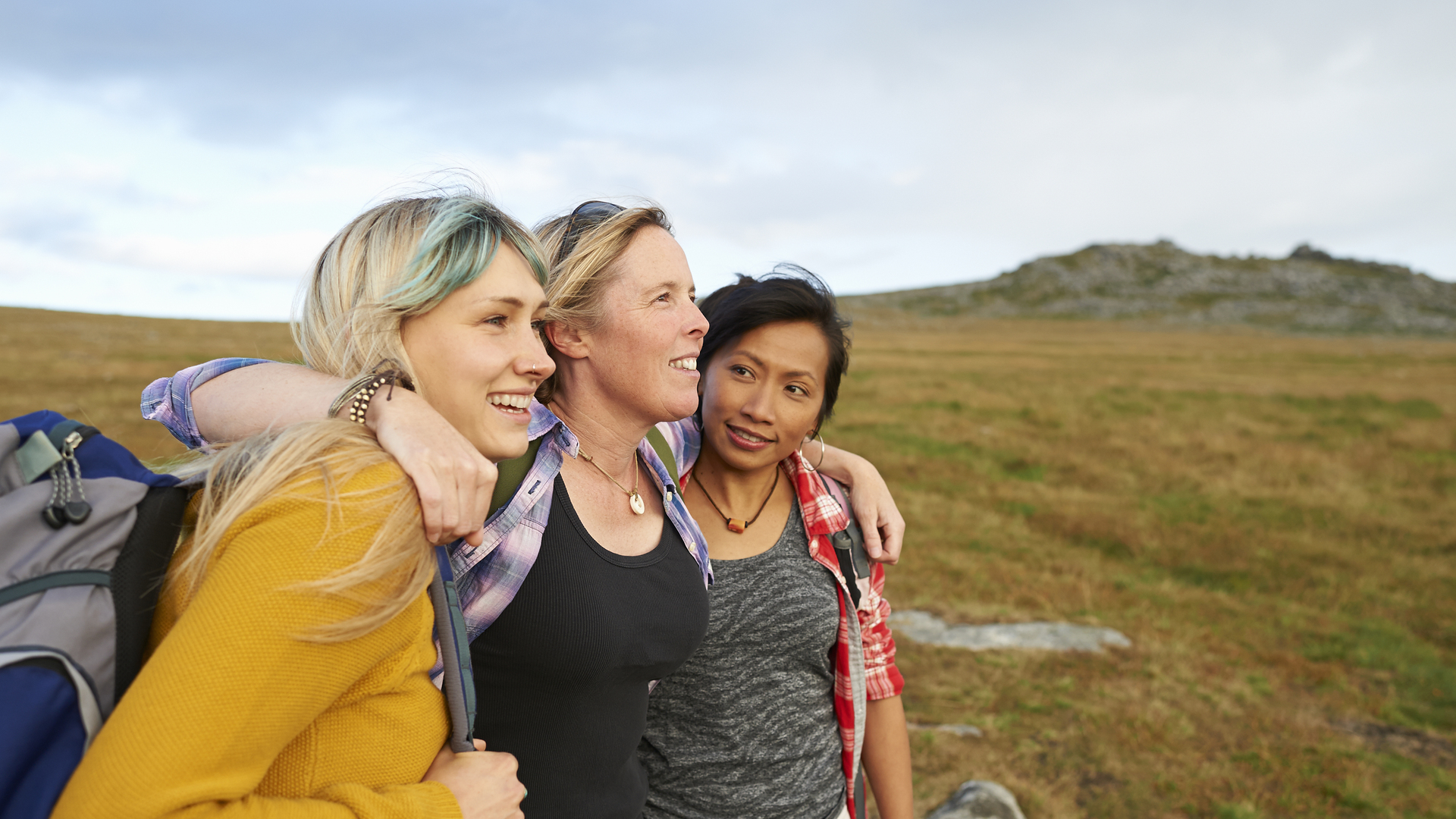 Happy and positive hiking friends huddle together on a rocky moorland.