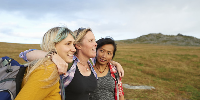 Happy and positive hiking friends huddle together on a rocky moorland.
