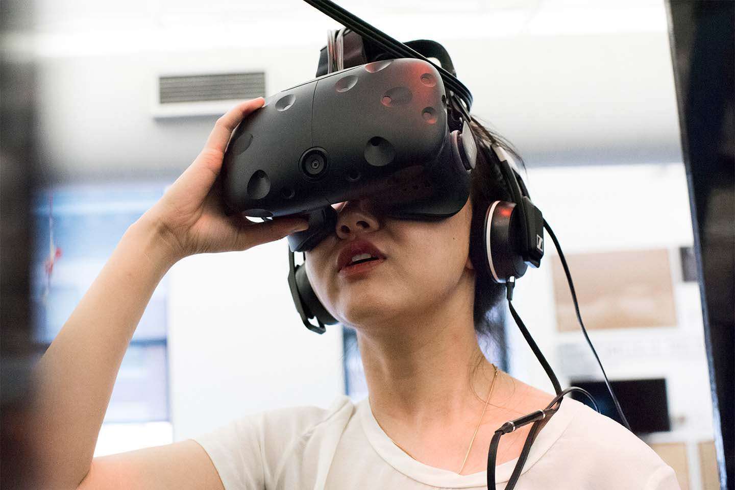 Young woman looks through a virtual reality device while wearing headphones