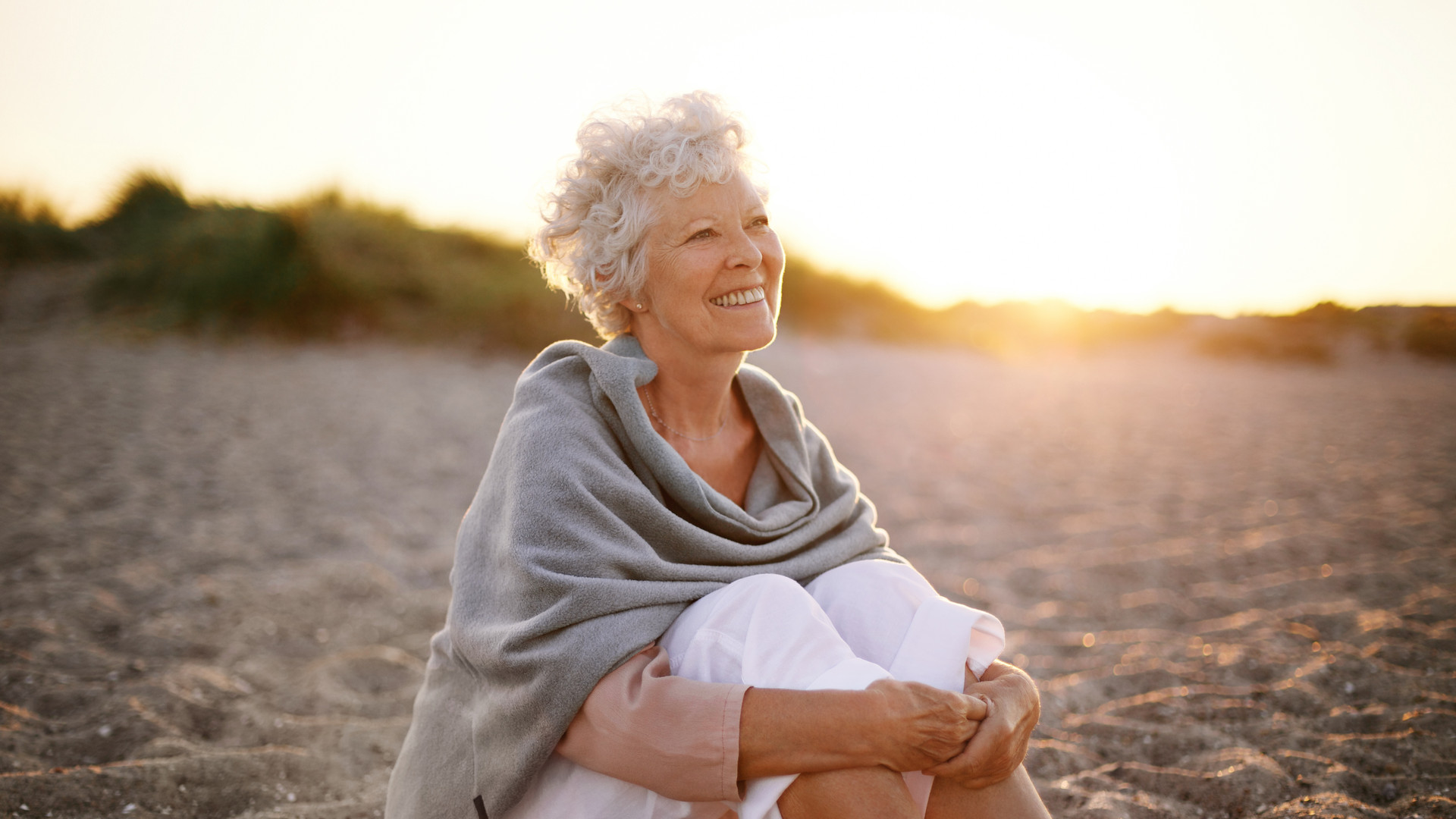 Cheerful old woman sitting on the beach