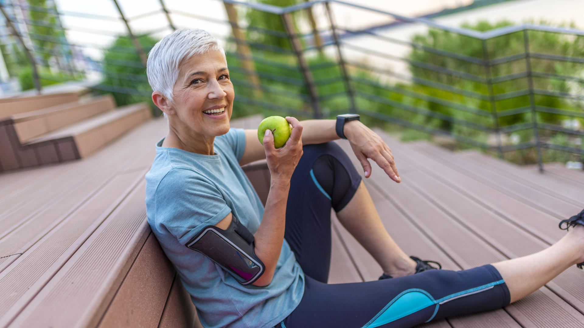 Mature athletic woman eating an apple after sports training