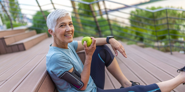 Mature athletic woman eating an apple after sports training