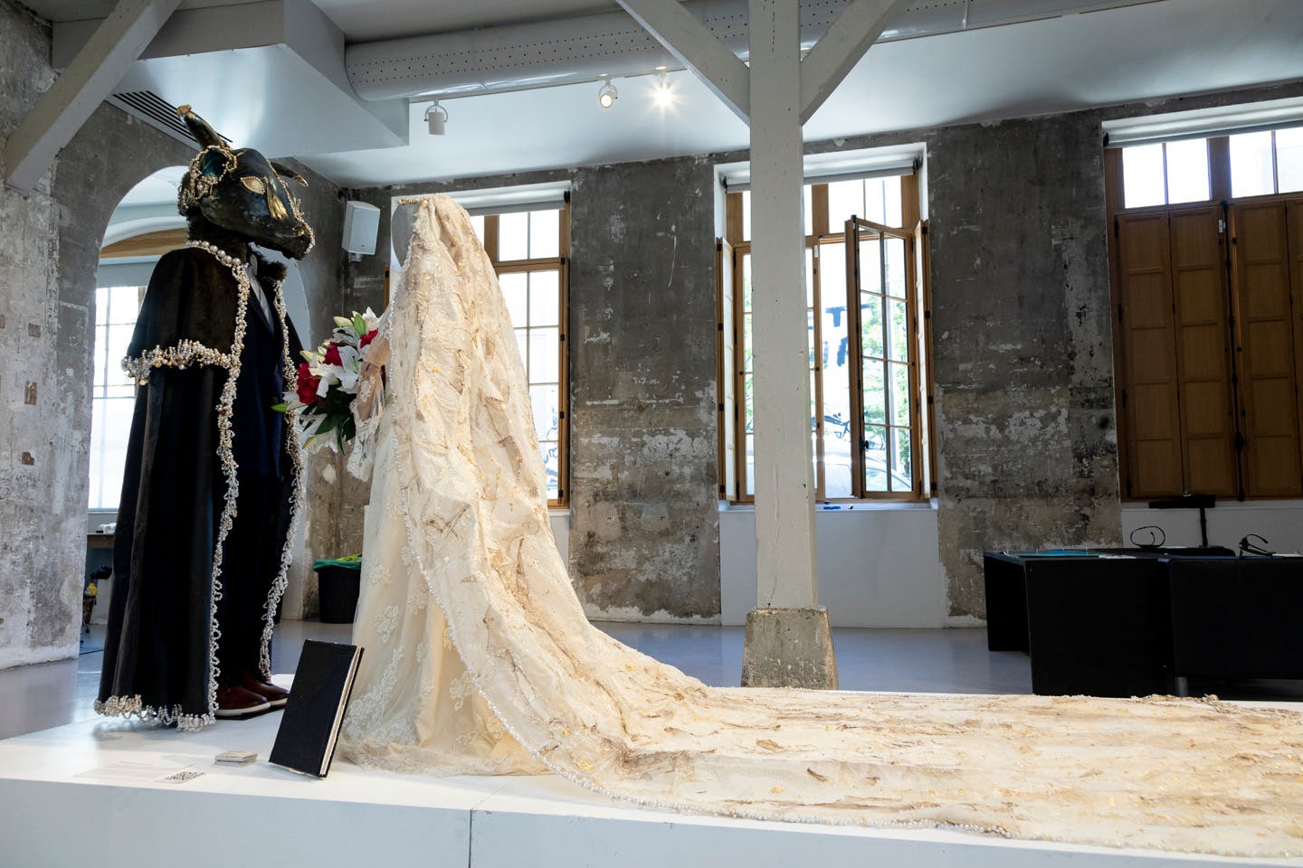 Mannequin figures dressed as bride and groom with animal mask in gallery