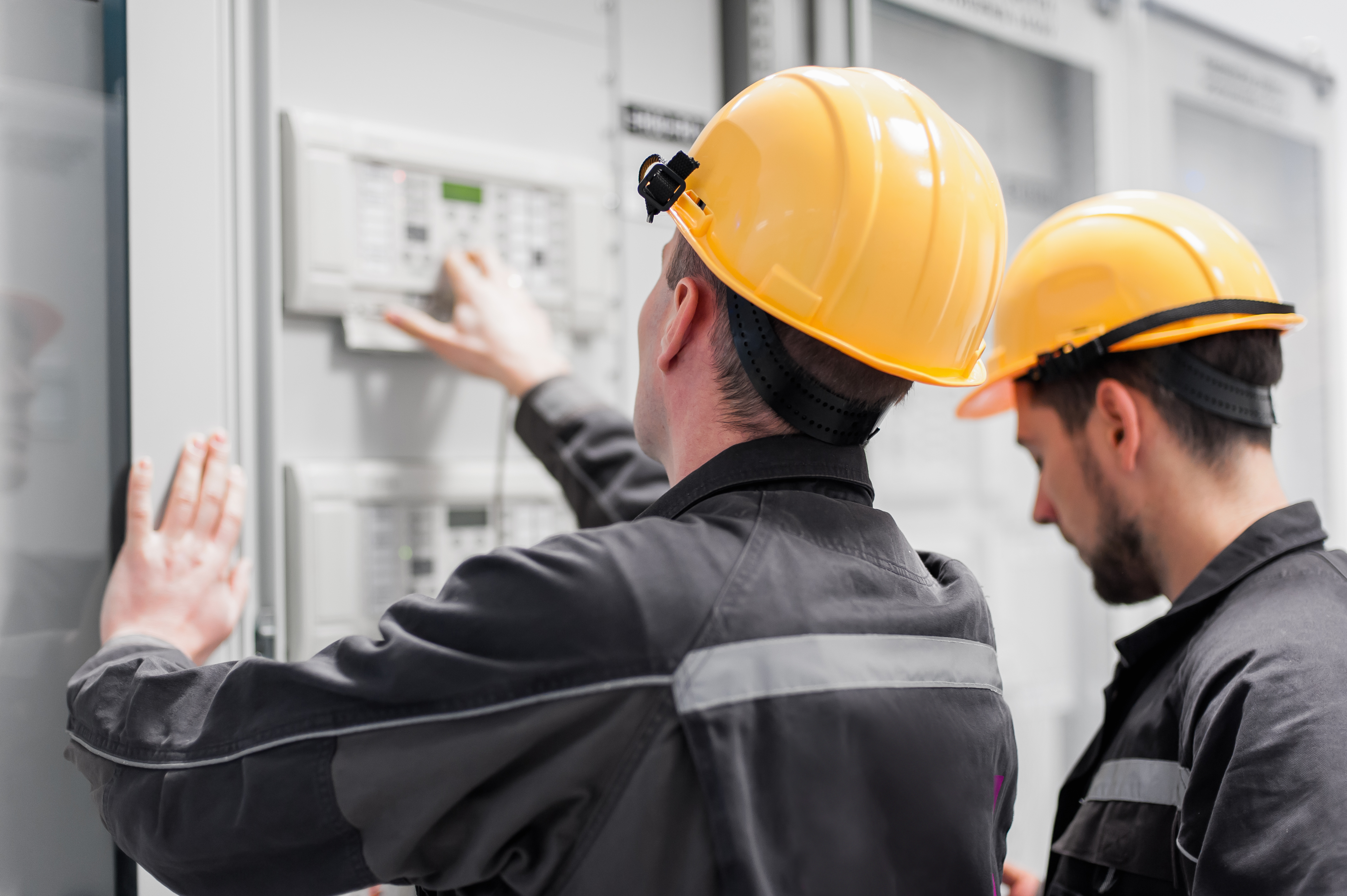 Two utility workers investigate a panel for industrial control systems cybersecurity