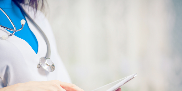 Doctor working on a digital tablet with copy space