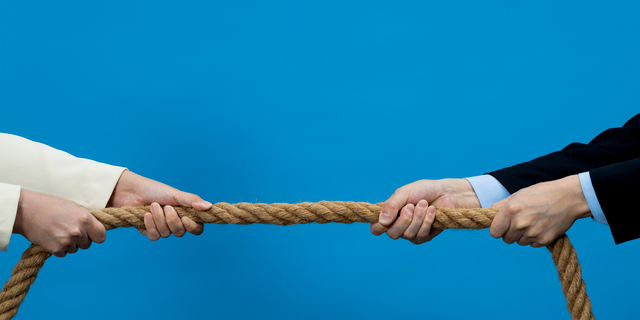 Two business person playing tug-of-war