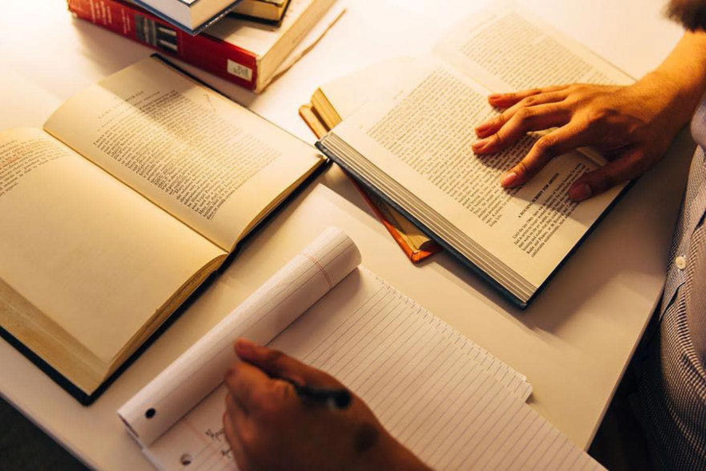 Student taking notes from book