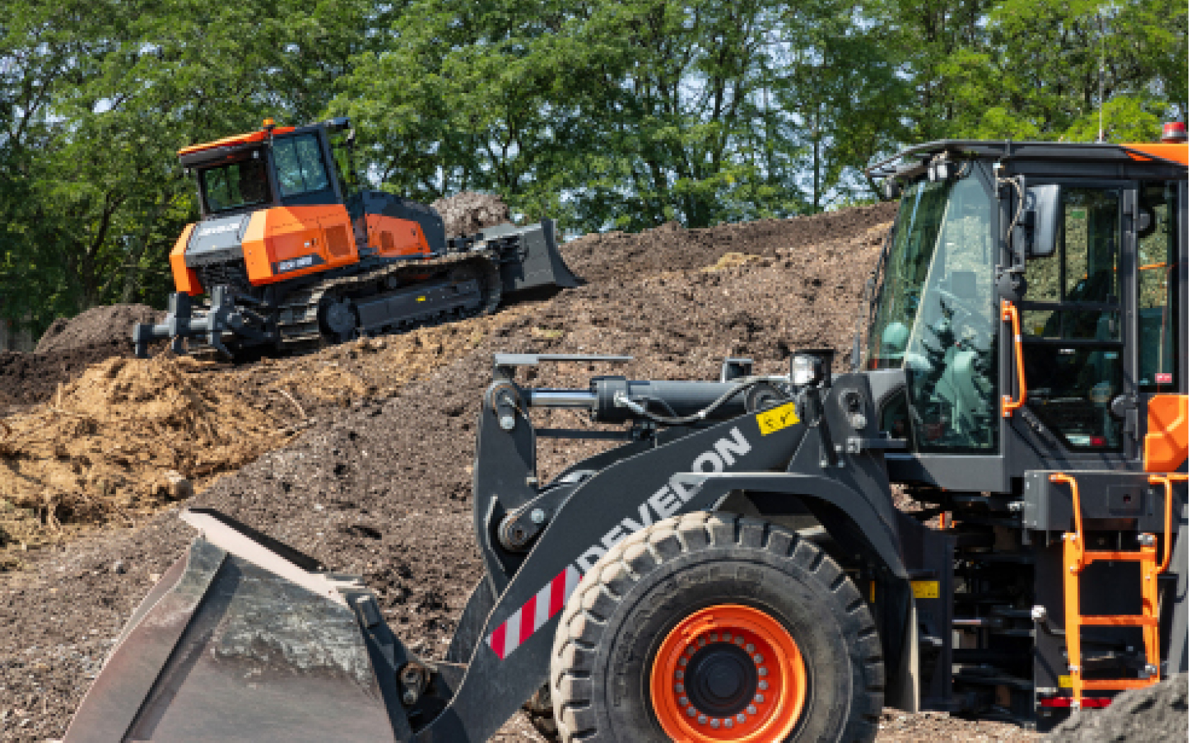A DEVELON dozer and wheel loader moving dirt on a job site.