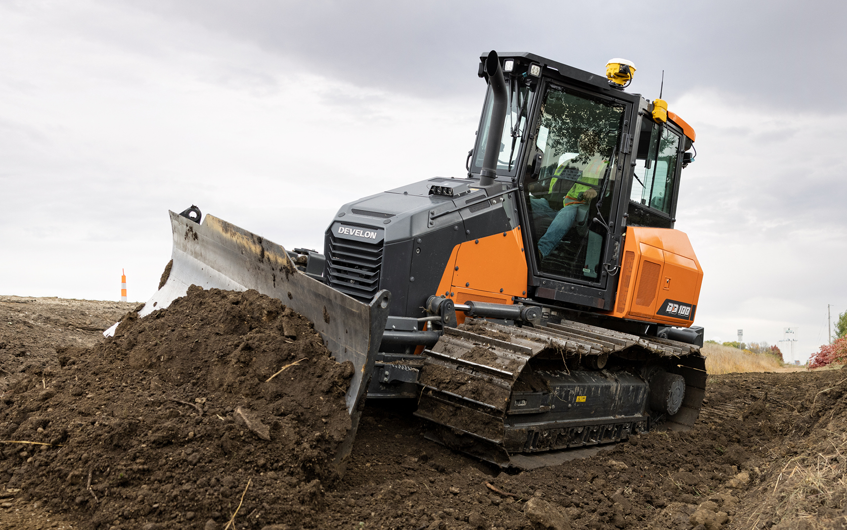 DEVELON DD100 dozer grading dirt on a job site.