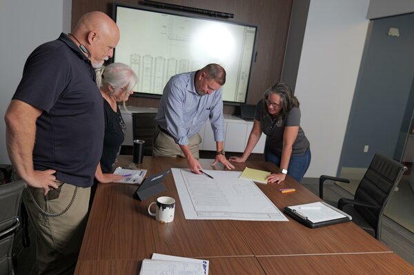 BICSI RCDD project managers and telecommunications engineers reviewing ICT site layout blueprints