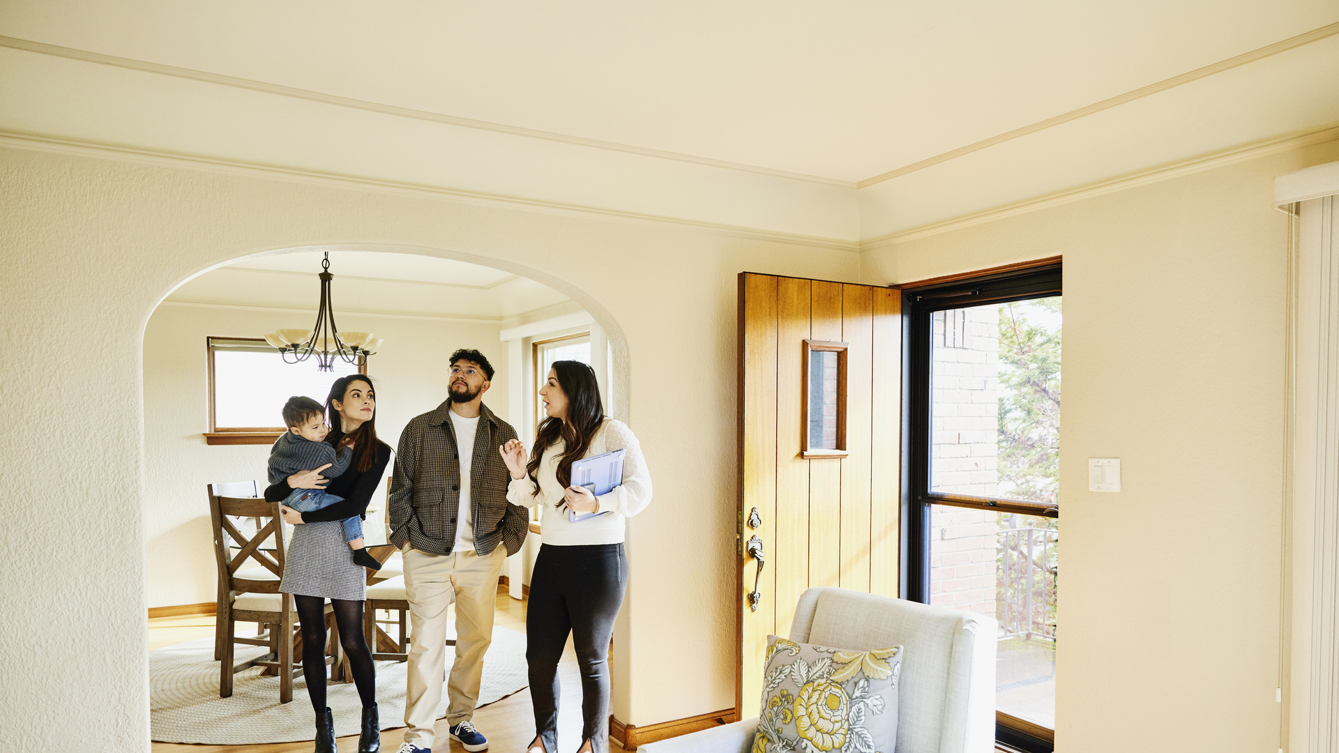 Wide shot of family looking at home for sale with real estate agent