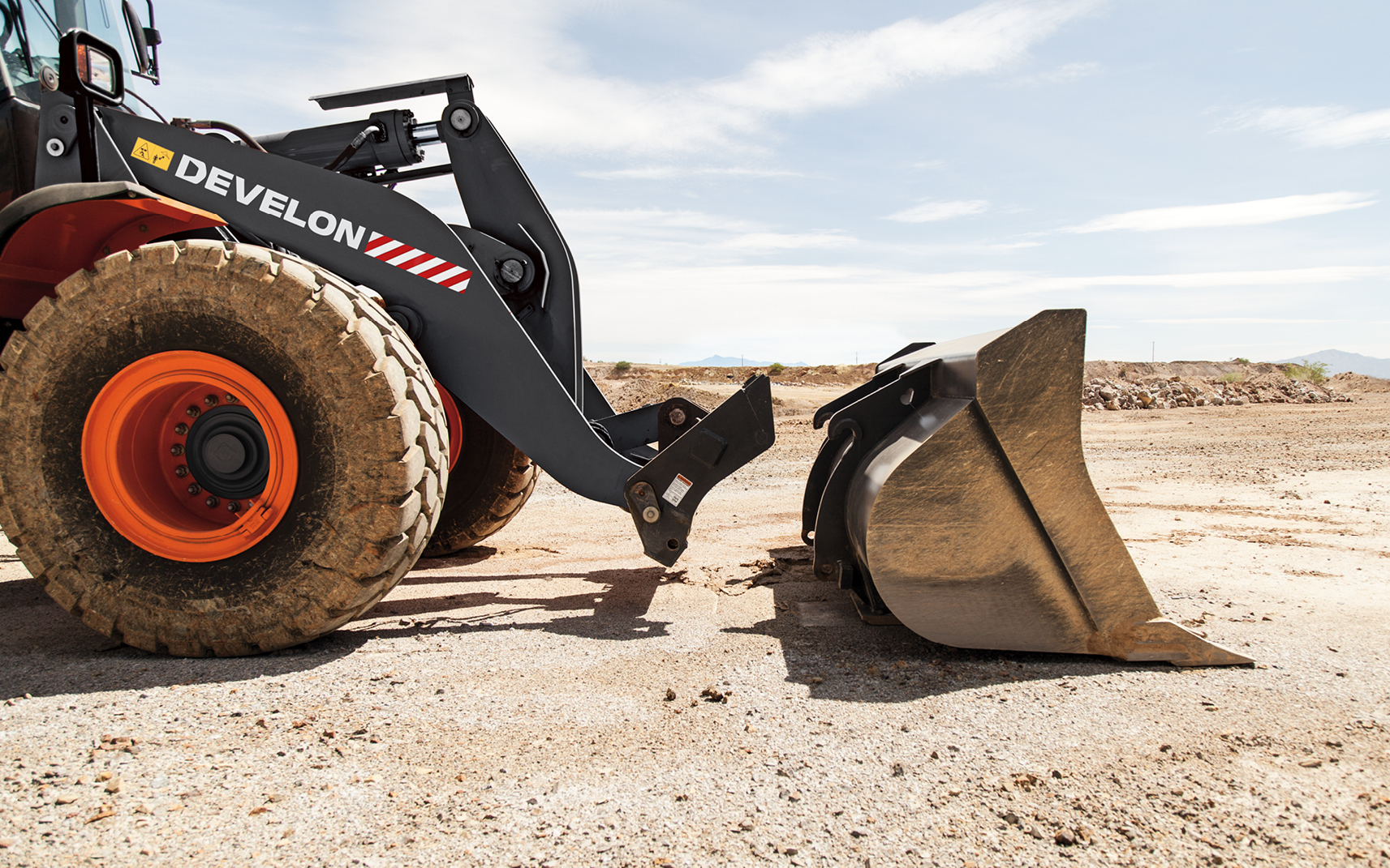 A wheel loader uses a quick coupler to attach a bucket, allowing for fast and easy changes of attachments.