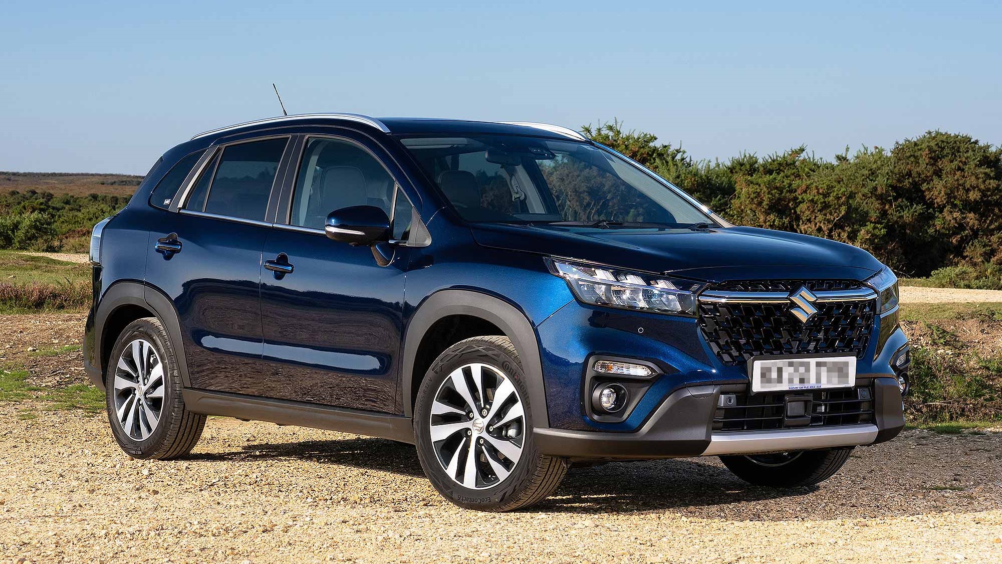 A dark blue Suzuki S-Cross parked on the side of a countryside road