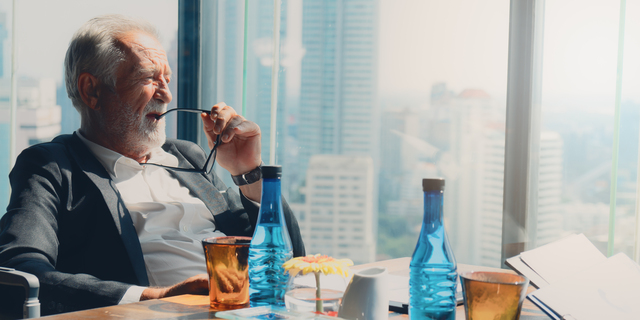 senior executive sitting by office window thinking of business strategy of company