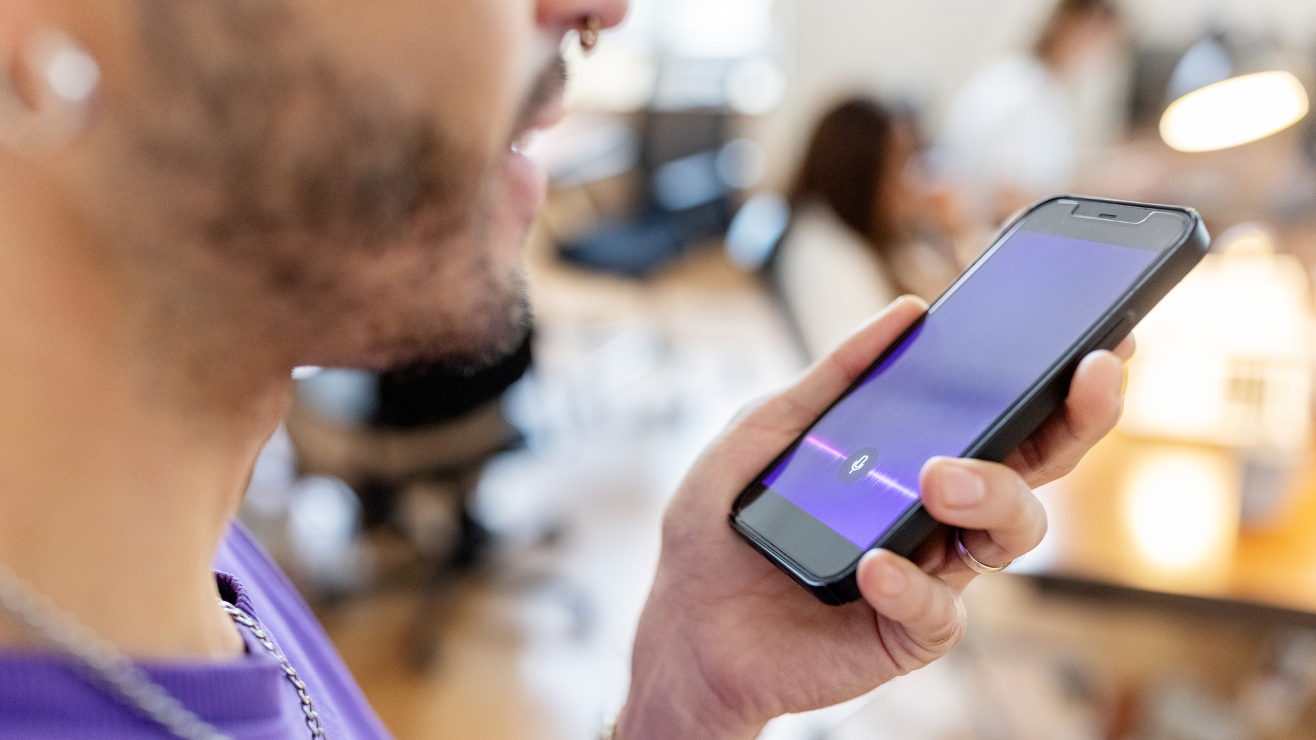 Close-up of man recording voice message on cellphone at office