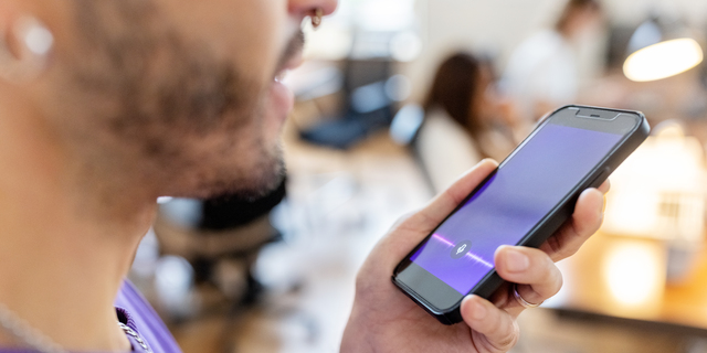 Close-up of man recording voice message on cellphone at office
