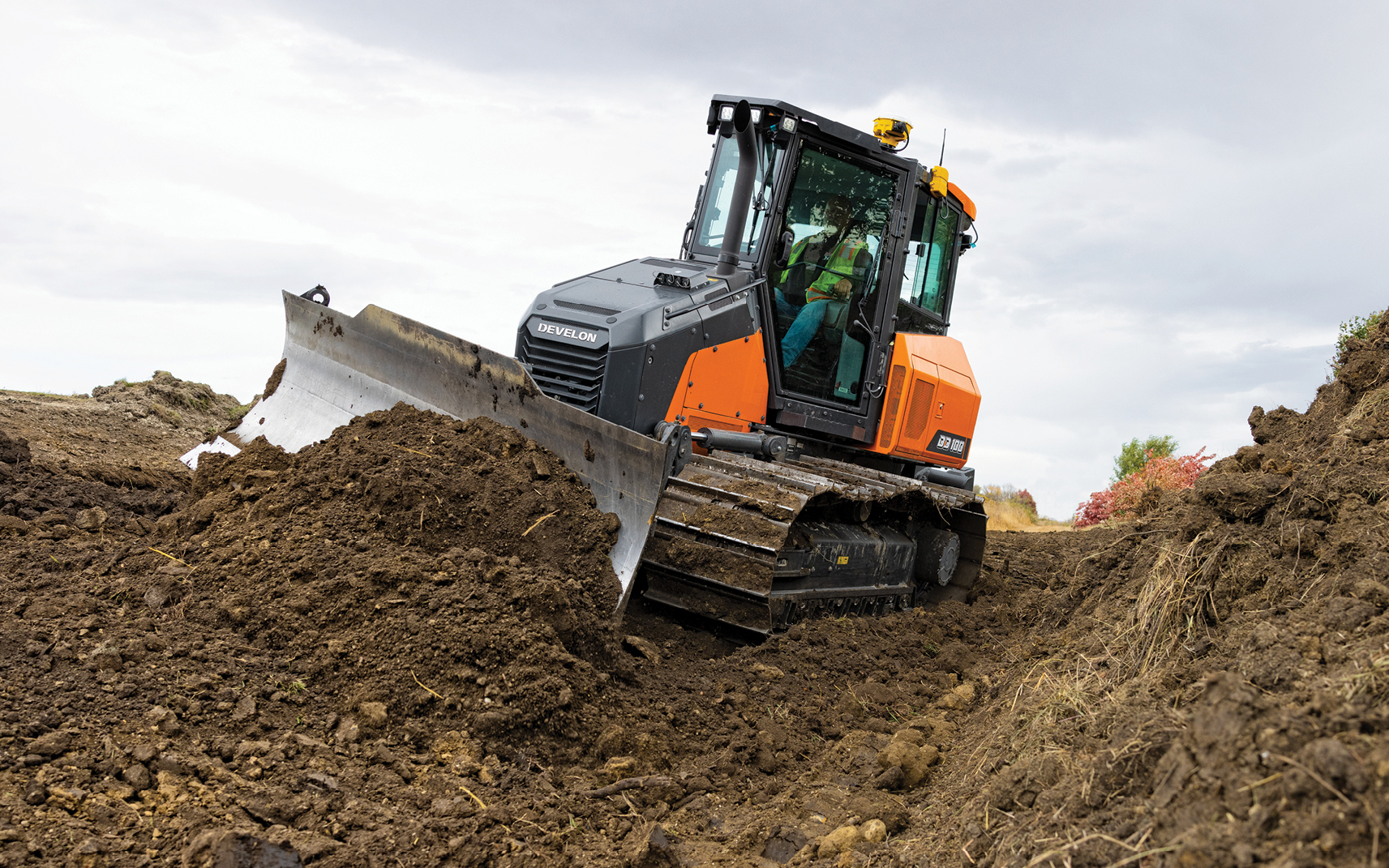 A DEVELON DD100 dozer equipped with a 3D grade control system pushes dirt with a blade.