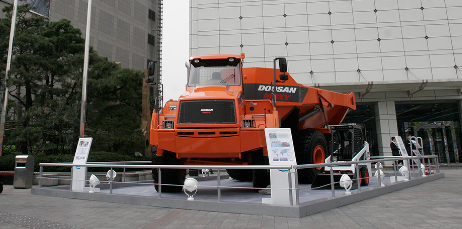 A Doosan articulated dump truck on display outside of a headquarters building.