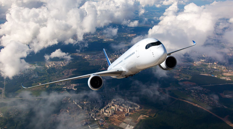 Commercial aircraft climbing above clouds