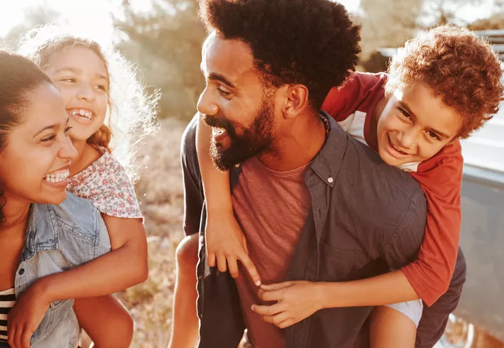 Parents giving their kids piggybacks, waist up, close up    