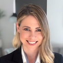 Smiling woman with blonde hair wearing a black suit jacket and white shirt. 