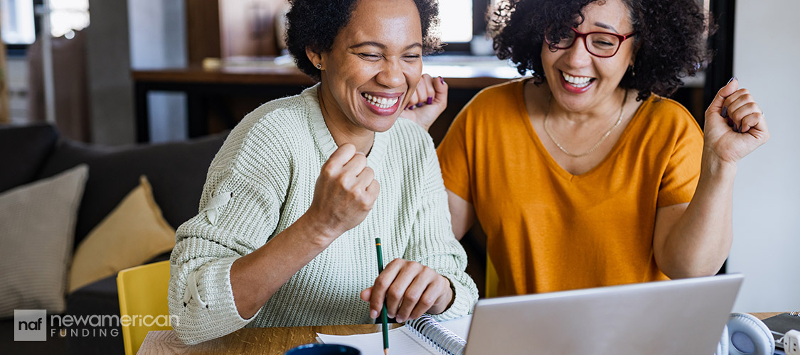 two women celebrating in front a laptop