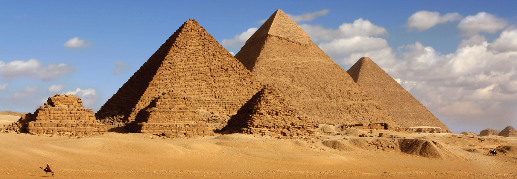 The ancient stone pyramids of Giza rise from the sandy Egyptian desert under a blue sky with scattered clouds.