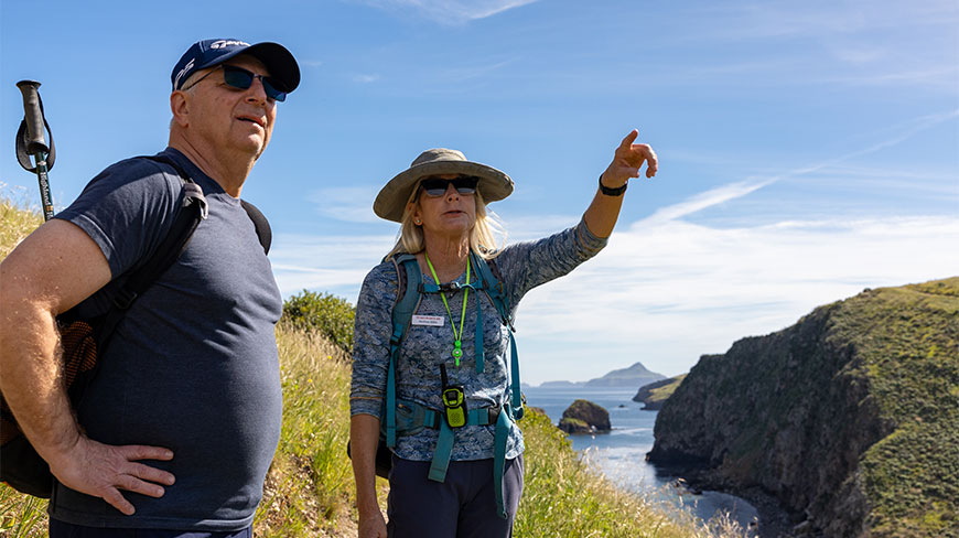 A naturalist points out features of the coastal landscape to a hiker on Santa Cruz Island in California's Channel Islands National Park.