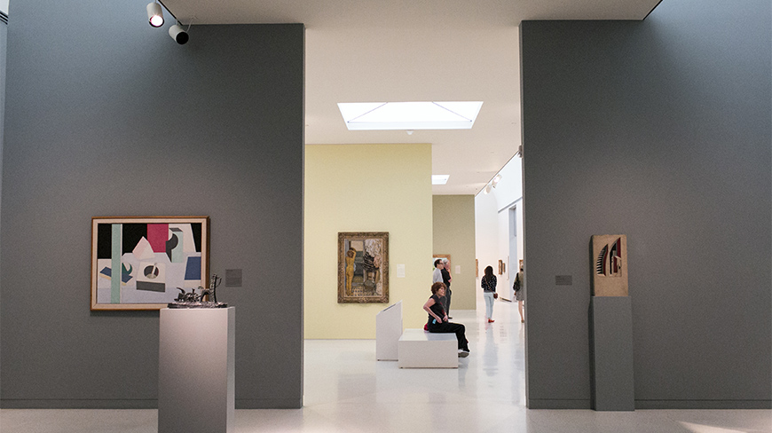 The sunlit interior of the Carnegie Museum of Art in Pittsburgh, Pennsylvania, with visitors viewing modern paintings and sculptures.