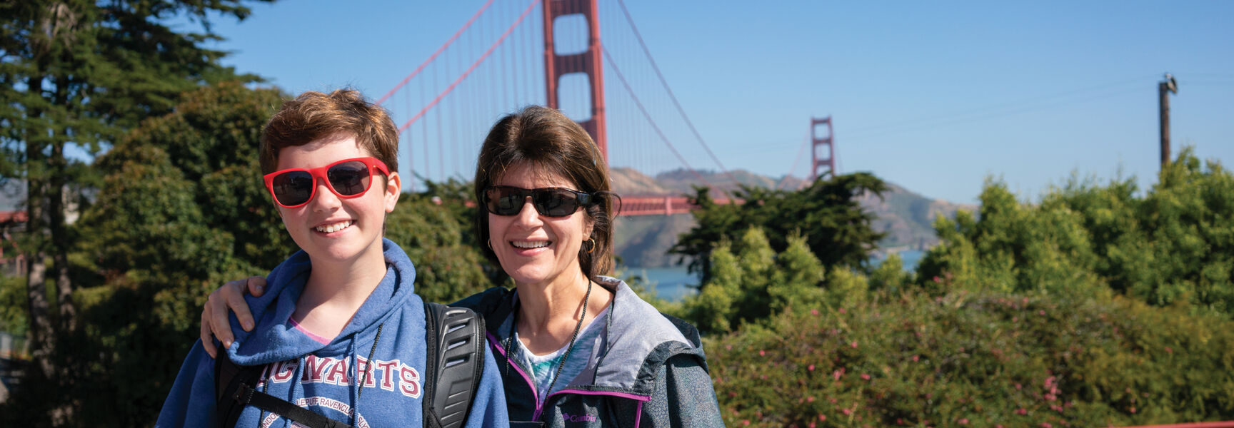 A woman and her grandchild smile together in California with the Golden Gate Bridge visible in the background.