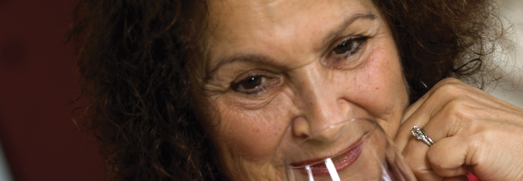 A woman with curly brown hair smiles while holding a wine glass on a tour through Spain and France.