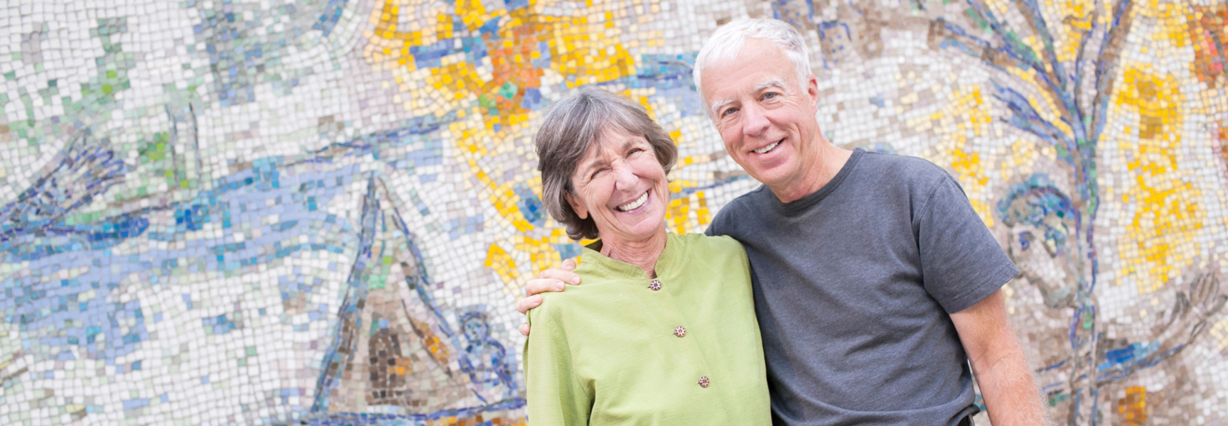A smiling couple stands in front of a colorful mosaic wall during an art and architecture tour in Chicago, Illinois.