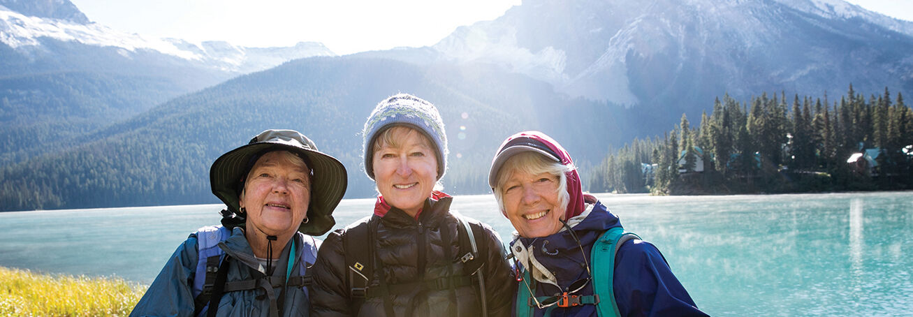 Road Scholars at the Great American Get-Together pose before the turquoise water and snow-dusted peaks of Emerald Lake in Alberta's Banff National Park.