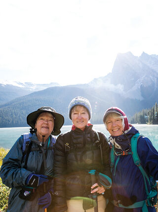 Road Scholars at the Great American Get-Together pose before the turquoise water and snow-dusted peaks of Emerald Lake in Alberta's Banff National Park.