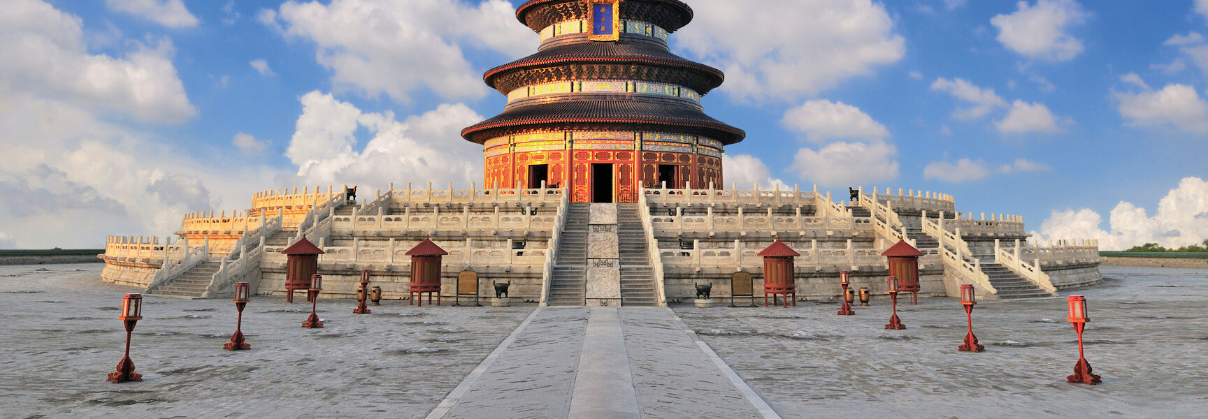 The Hall of Prayer for Good Harvests at the Temple of Heaven in Beijing, China, under a bright blue sky with scattered white clouds.