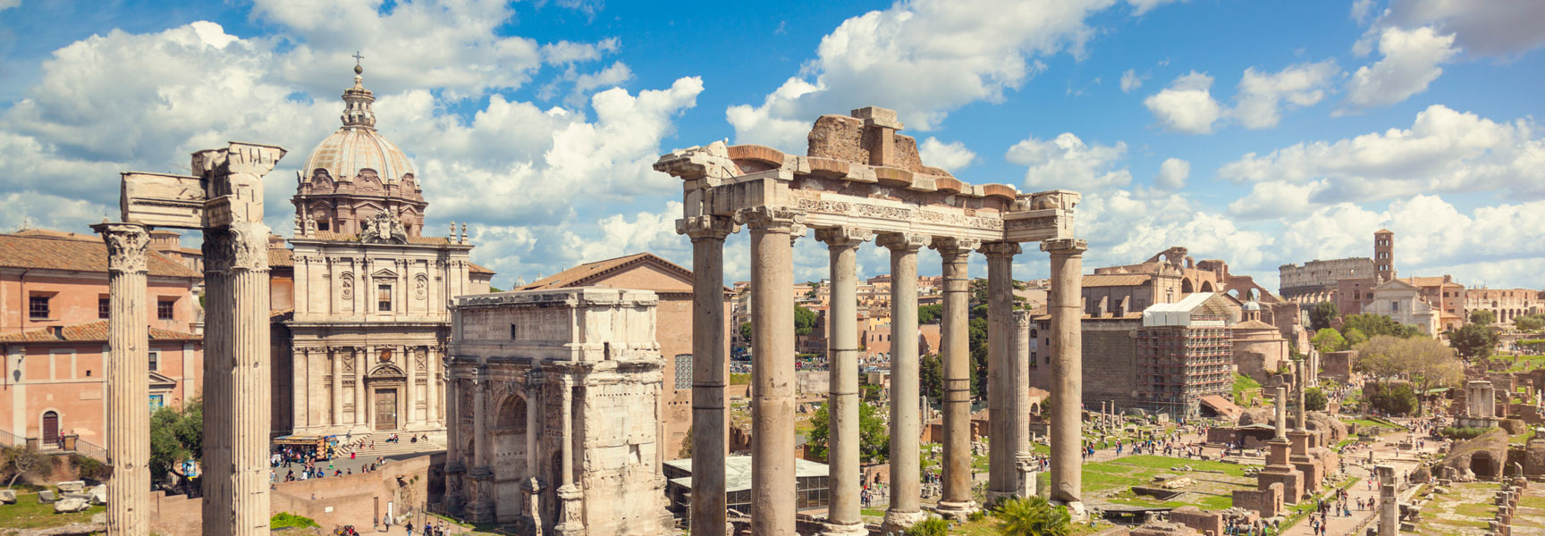 A wide, sunny day view of the ancient Roman Forum in Rome, Italy, with historic columns, arches, and tourists exploring the ruins.
