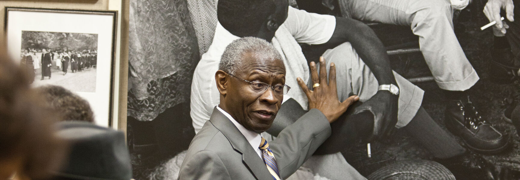 A guide in a suit gestures toward a large photograph of Martin Luther King Jr. during a Civil Rights Movement history tour in Georgia.