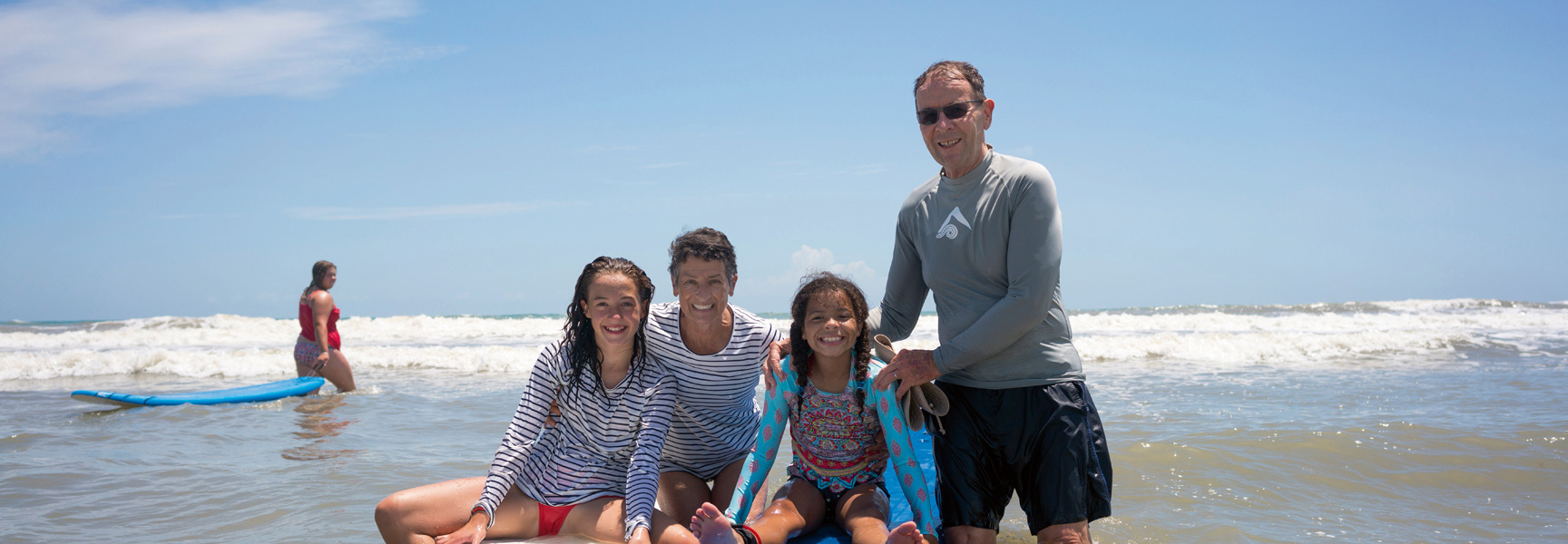 Grandparents and two grandchildren enjoy a surfing lesson in the ocean in Florida on a sunny day.