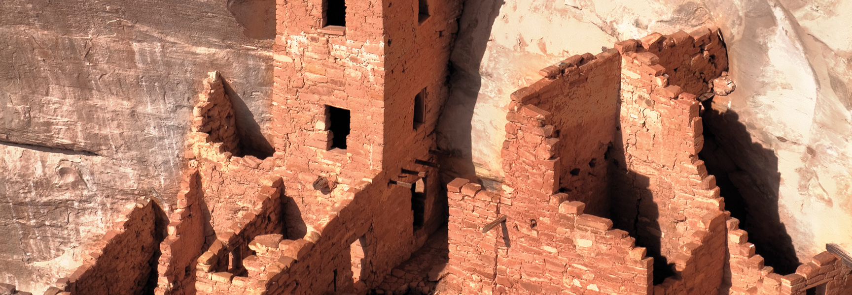 Ancient cliff dwellings are built into the side of a sandstone canyon wall in Mesa Verde National Park, Colorado.