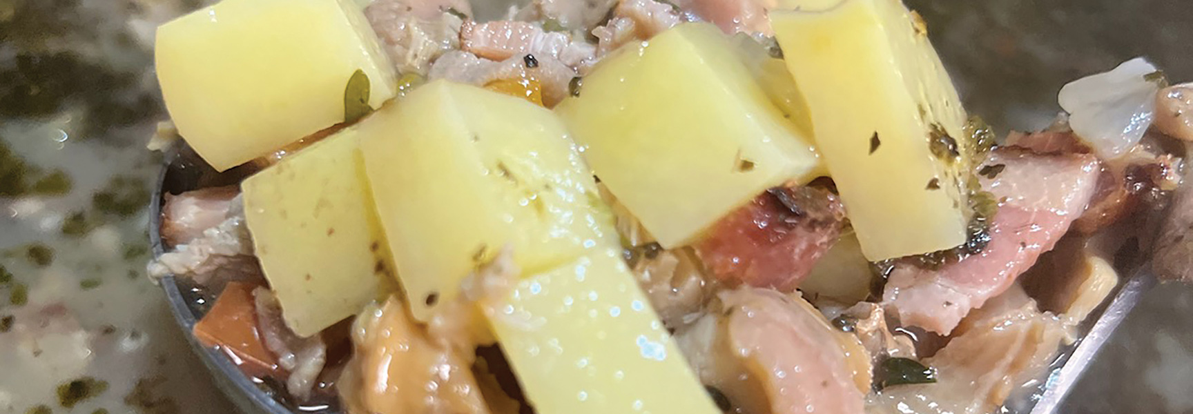 A close-up of a spoonful of Chincoteague clam chowder with potatoes and bacon from a sea-to-table meal in Virginia.