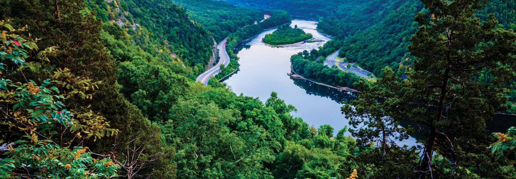 A scenic view from above shows a river winding through the lush, green mountains of the Poconos in Pennsylvania.